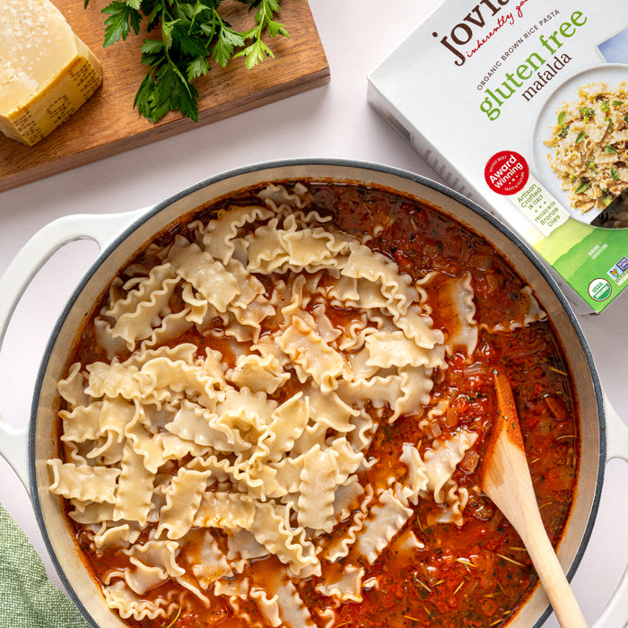 Lasagna soup with Jovial brown rice gluten free Mafalda pasta simmering in pot with wooden spoon and product box