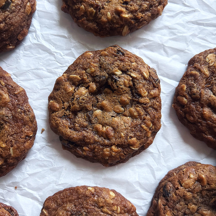 Top-down view of einkorn oatmeal raisin cookies showing chewy texture, visible oats and raisins on crumpled parchment