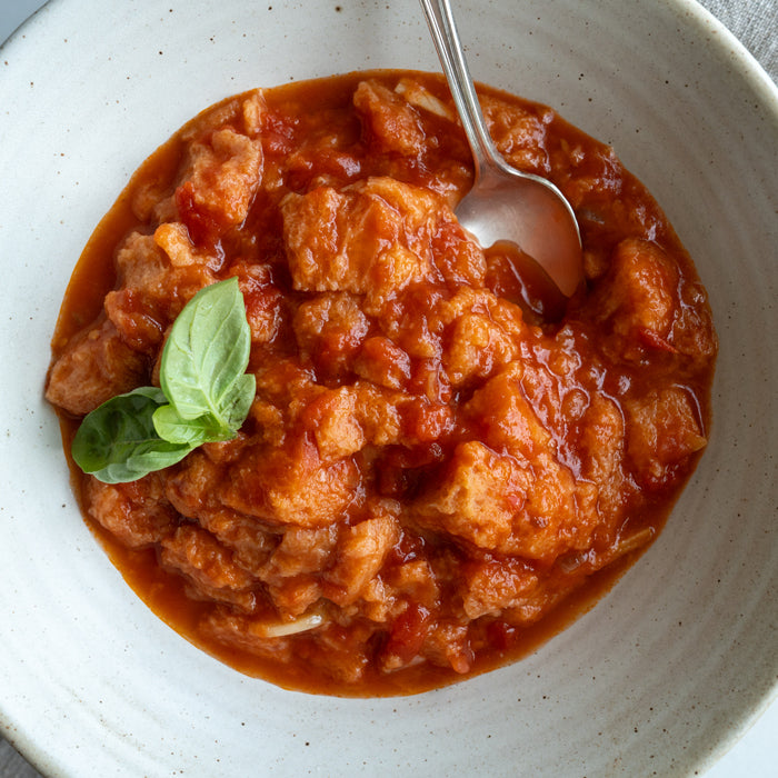 A bowl of pappa al pomodoro (bread cubes in tomato soup) with a few basil leaves