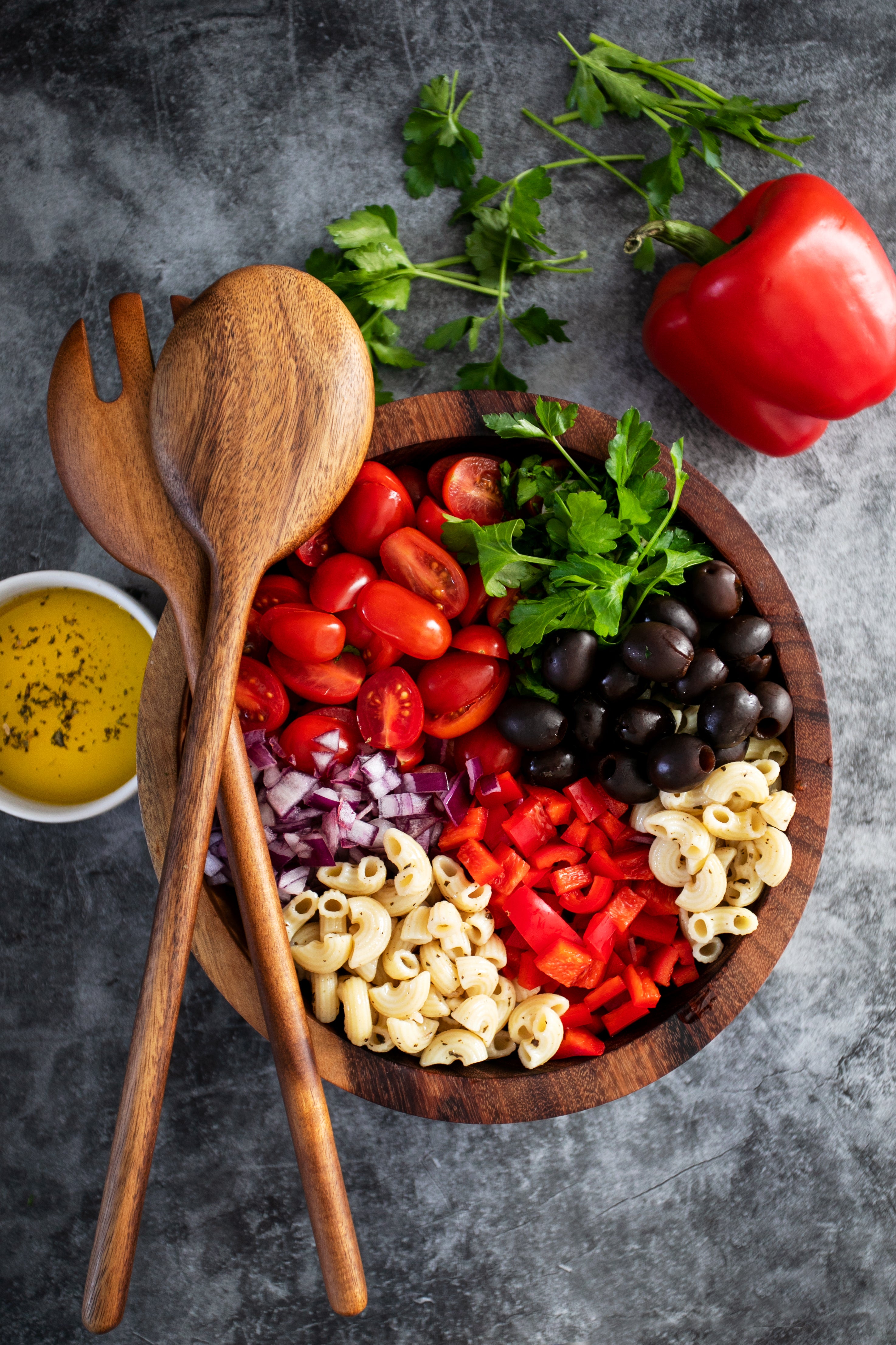 Top-down view of gluten-free elbow pasta salad with cherry tomatoes, olives, red pepper, red onion and parsley