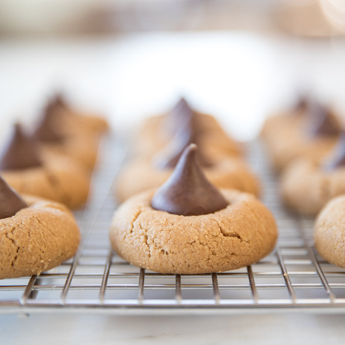 Close-up of Einkorn peanut butter blossom cookies showing chocolate kiss centers and cracked tops on a cooling rack