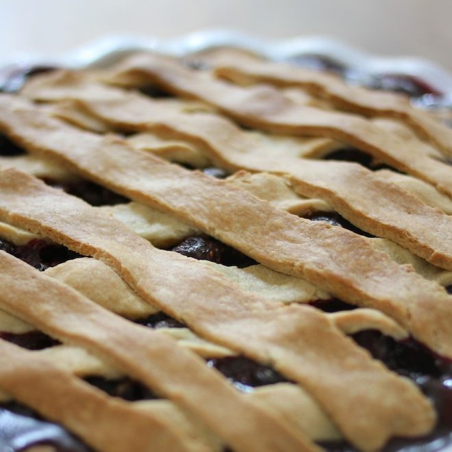 Close-up of lattice-top blueberry pie showcasing golden einkorn crust and visible blueberry filling with blurred background