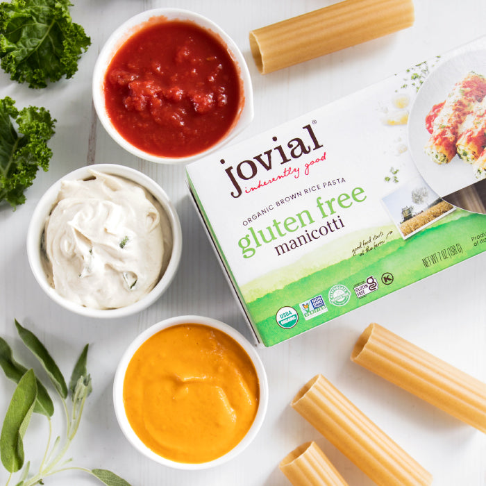 Pumpkin-sage filled organic gluten free brown rice manicotti on a plate with bowls of sauces and the product box on white