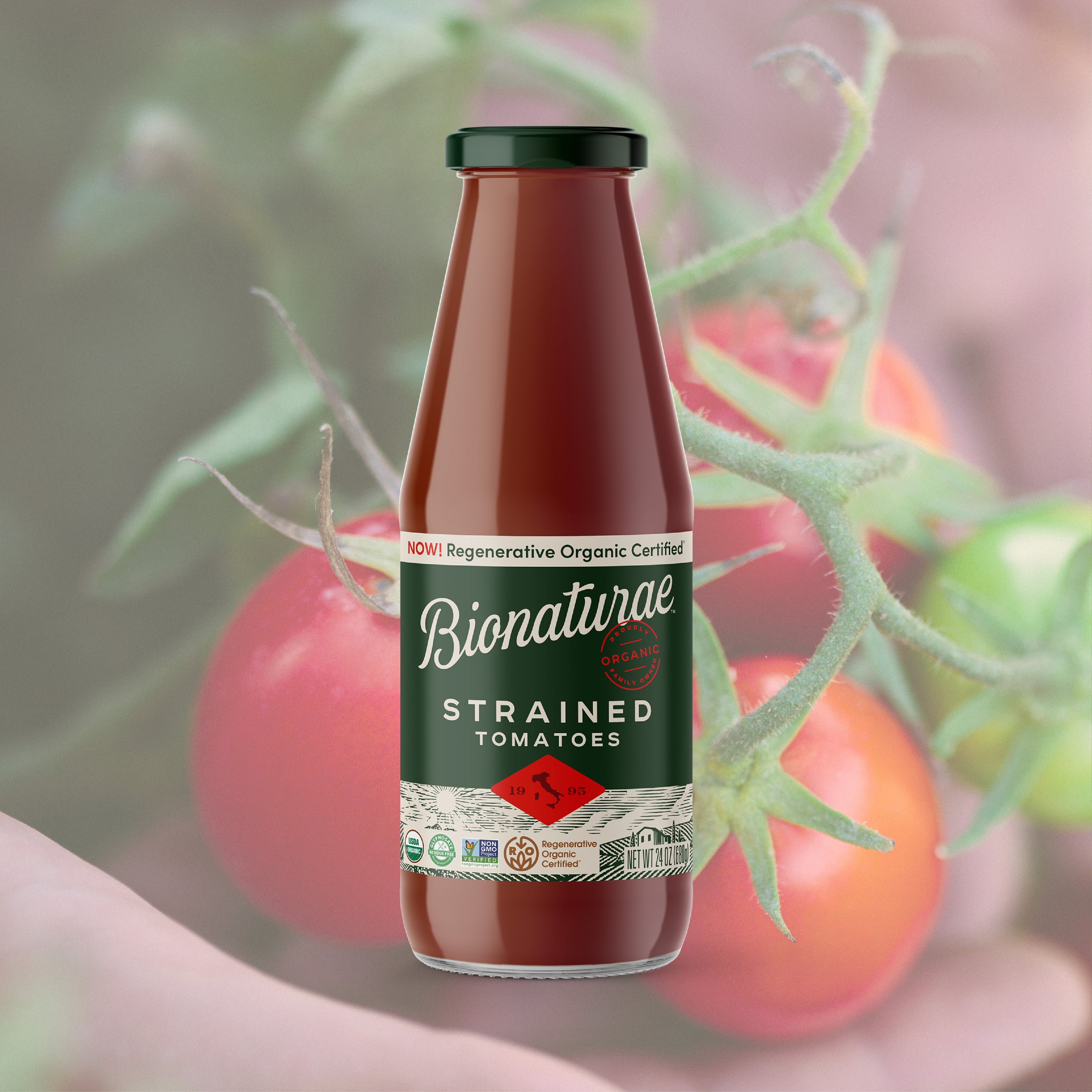 Front view of Bionaturae strained tomatoes bottle with green label and certified band against blurred tomatoes