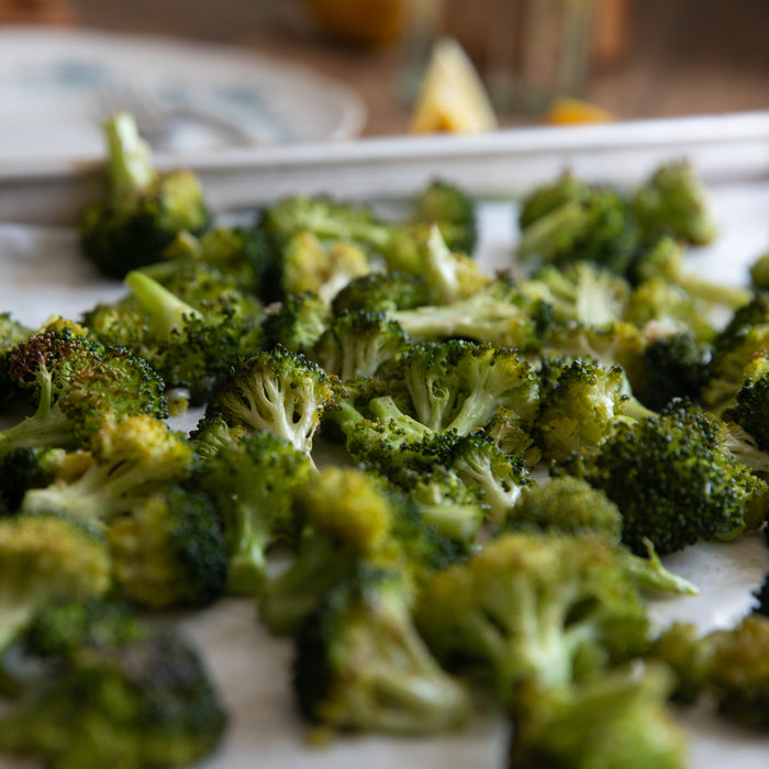 Close-up of roasted broccoli florets, lightly charred, on a parchment-lined baking sheet
