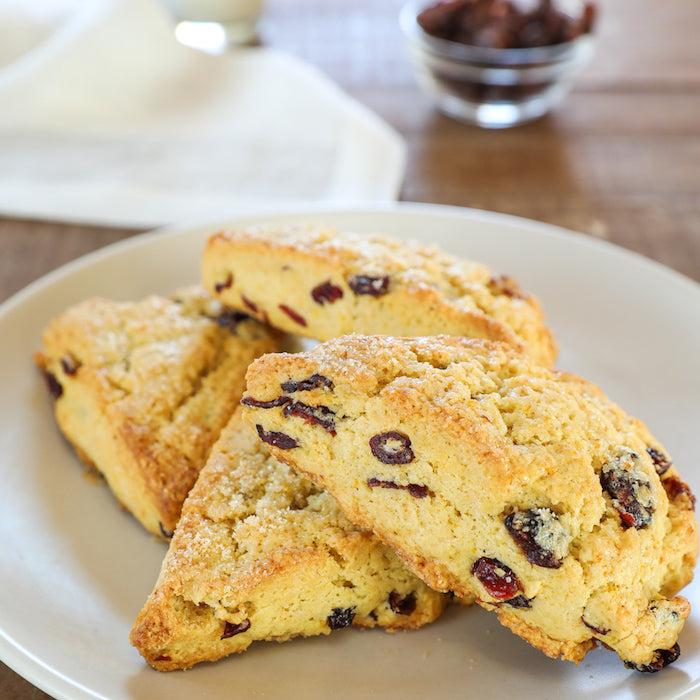 Close-up of three Einkorn orange cranberry scones with golden crust and visible cranberries on a plate