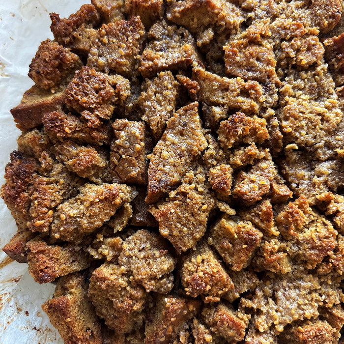 Top-down view of maple caramel sourdough bread pudding with cubed Einkorn bread and golden caramelized crust on parchment