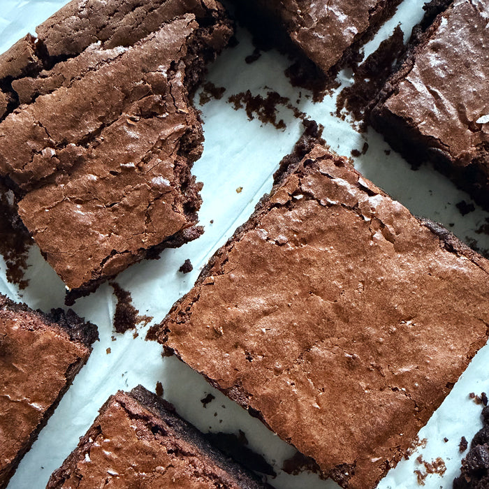Overhead close-up of sourdough einkorn brownies showing crackly tops and fudgy centers on parchment paper