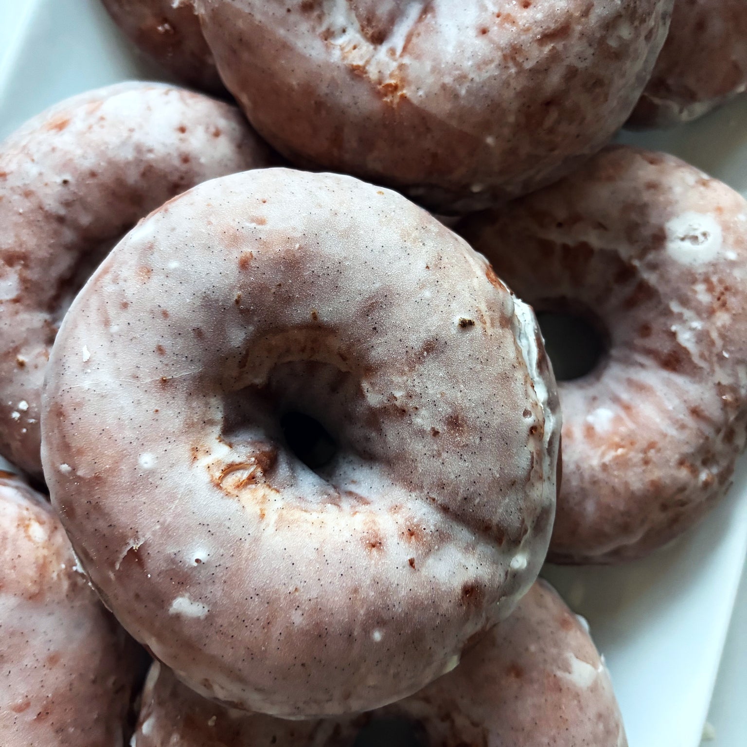 Close-up of sourdough glazed donuts showing light sugar glaze and airy crumb on a white plate