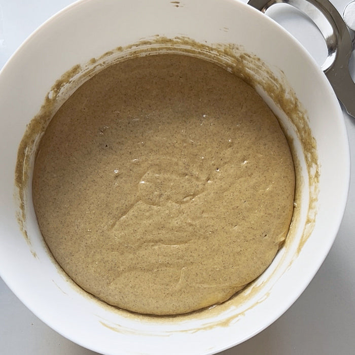 Top-down view of sourdough Einkorn pancake batter with smooth, thick texture in a white mixing bowl on a light countertop