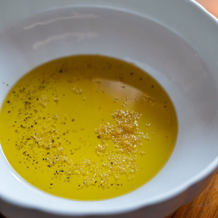 Bowl of olive oil seasoned with lemon zest and cracked black pepper