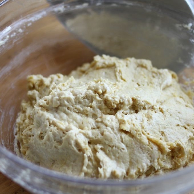 Einkorn sandwich bread dough resting in a glass mixing bowl with a metal spatula