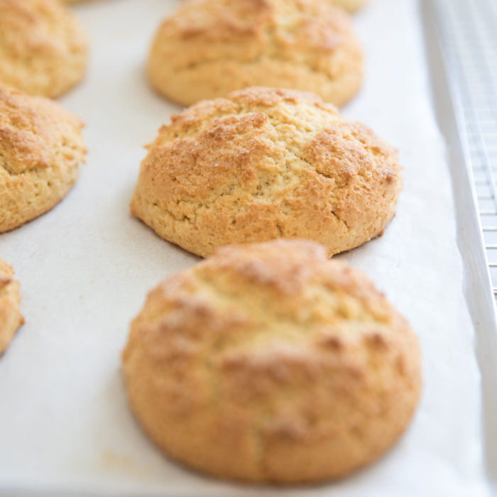 Close-up of einkorn shortcakes on a parchment-lined baking sheet showing golden-brown, cracked tops and tender crumb
