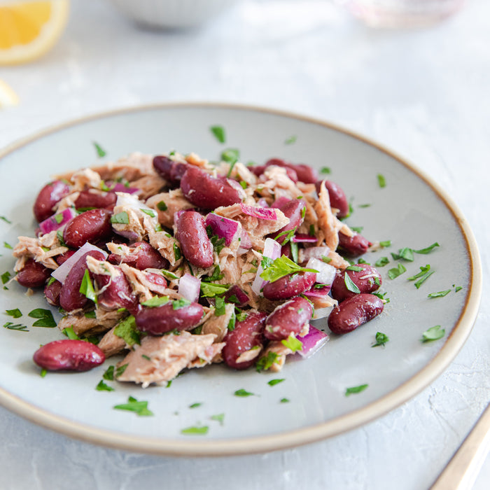 Tuna and kidney bean salad on a gray plate with parsley and chopped red onion