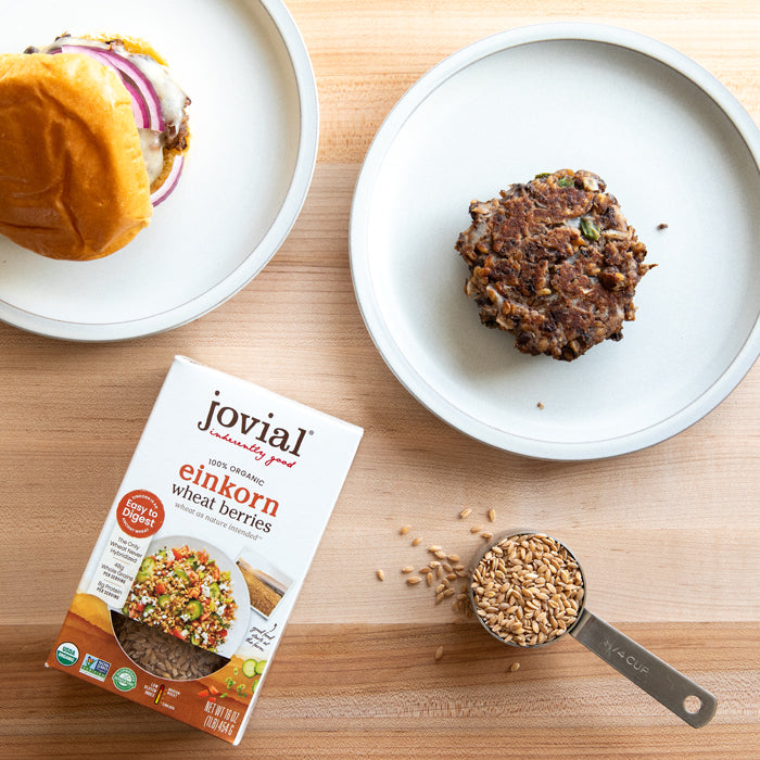 Black bean and wheat berry patty beside a box of Jovial organic einkorn wheat berries and a 1/4 cup scoop on a wood surface