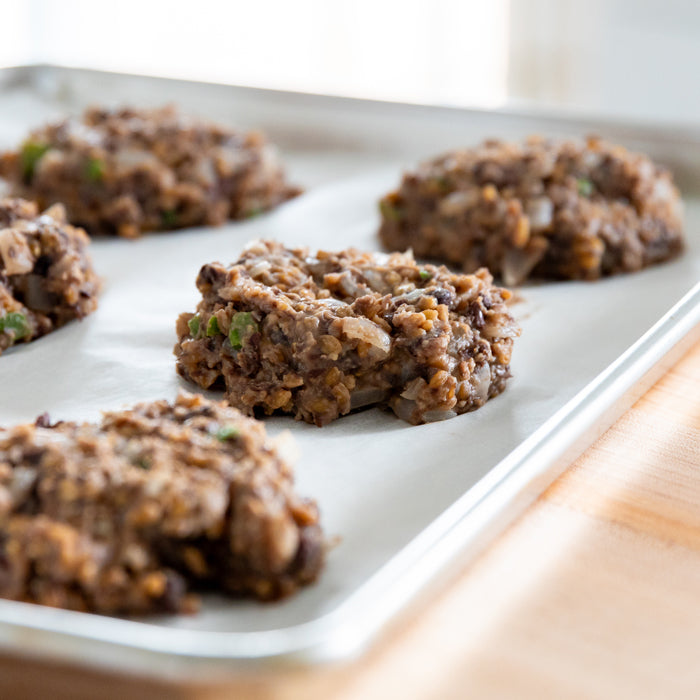 Close-up of wheat berry and black bean veggie burger patties showing texture and einkorn wheat berries on a baking sheet