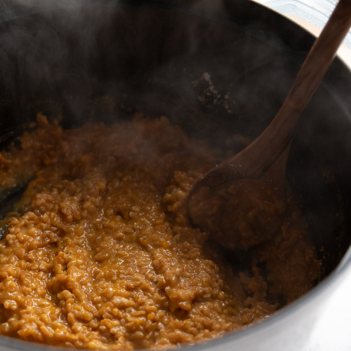 Einkorn wheat berry risotto with butternut squash being stirred in a pot with a wooden spoon