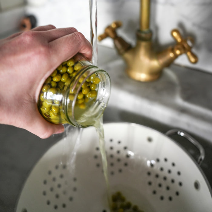 draining a jar of Jovial peas into a colander