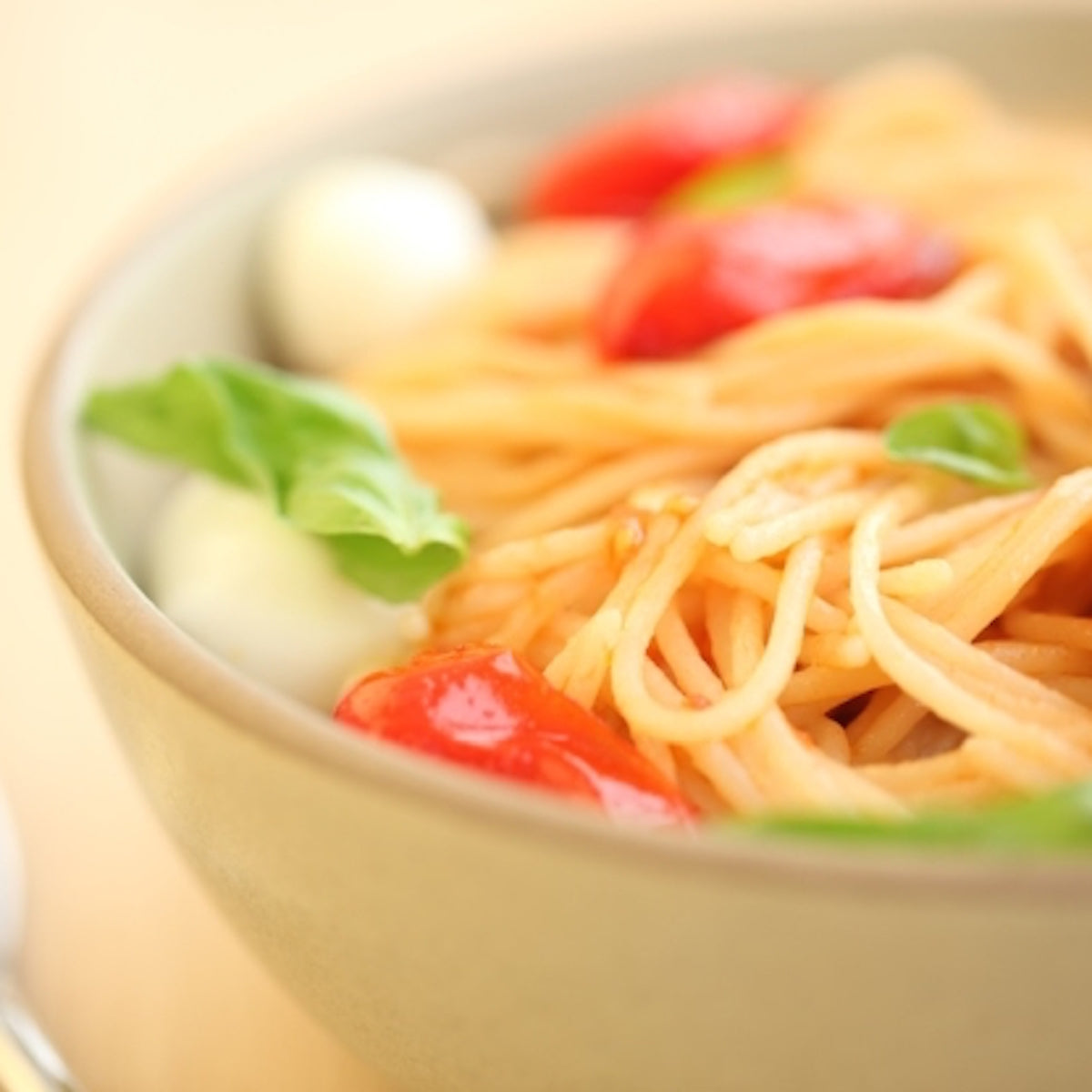 Bowl of cooked brown rice spaghetti with cherry tomatoes and basil