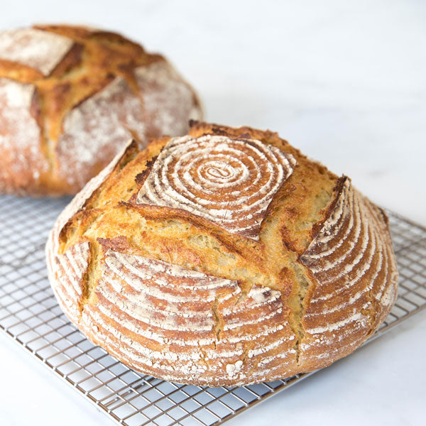 Three-quarter view of Einkorn sourdough loaf showing golden crust, banneton spiral pattern, and cooling rack
