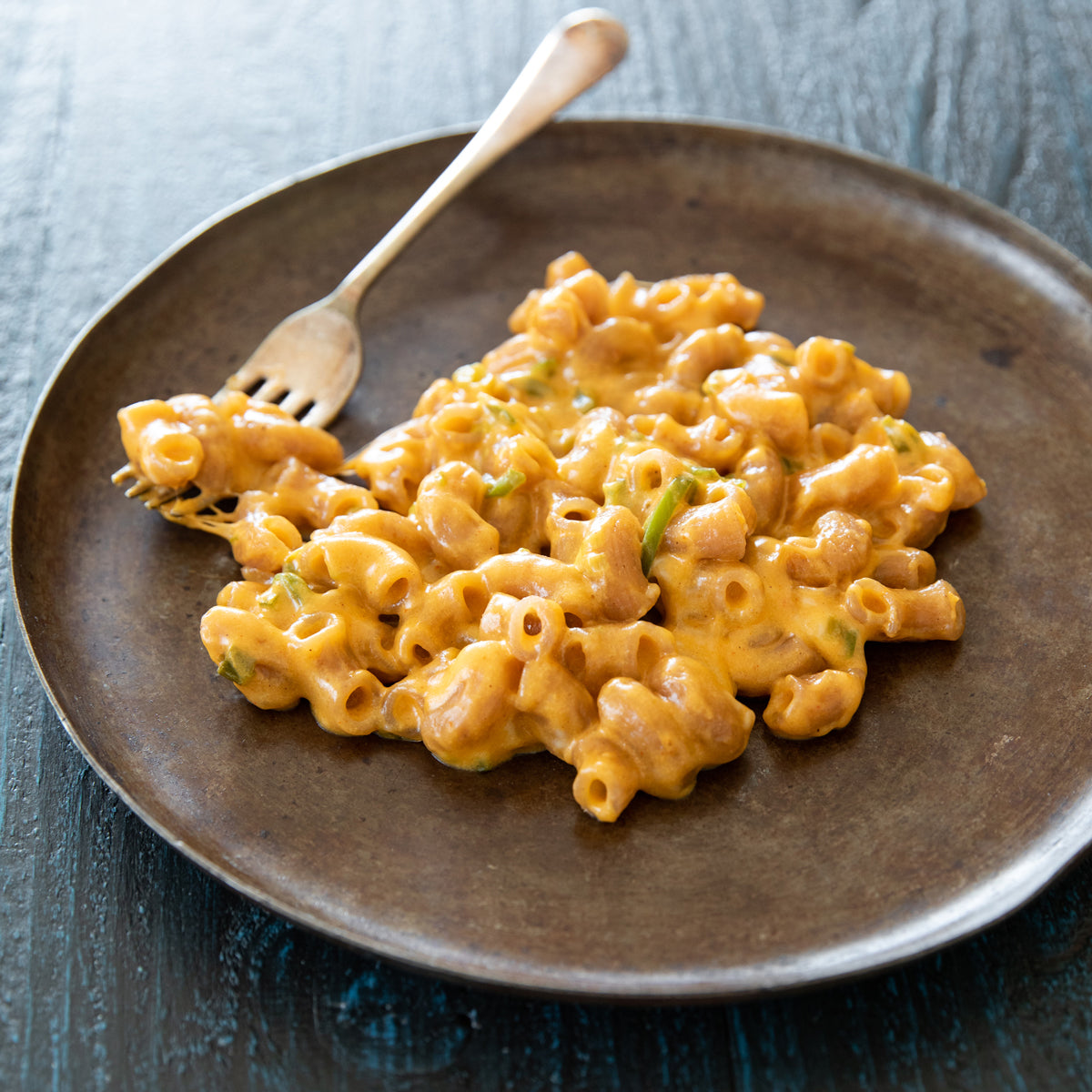 Creamy mac and cheese made with organic grain-free cassava elbow pasta on a brown plate with a fork