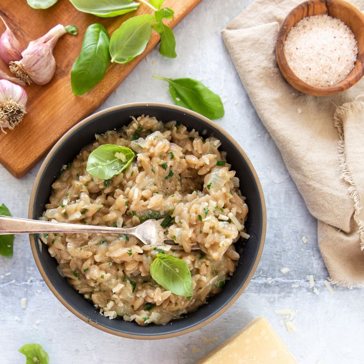 Bowl of Organic Grain Free Cassava Orzo served with basil and a lemon wedge on a rustic wooden table