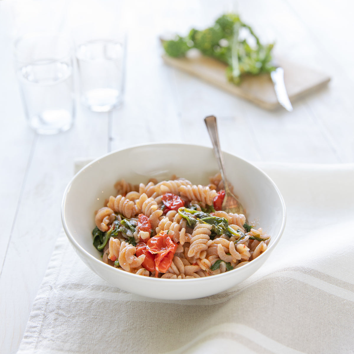 Bowl of organic grain-free cassava fusilli pasta served in a white bowl with a fork on a light table setting