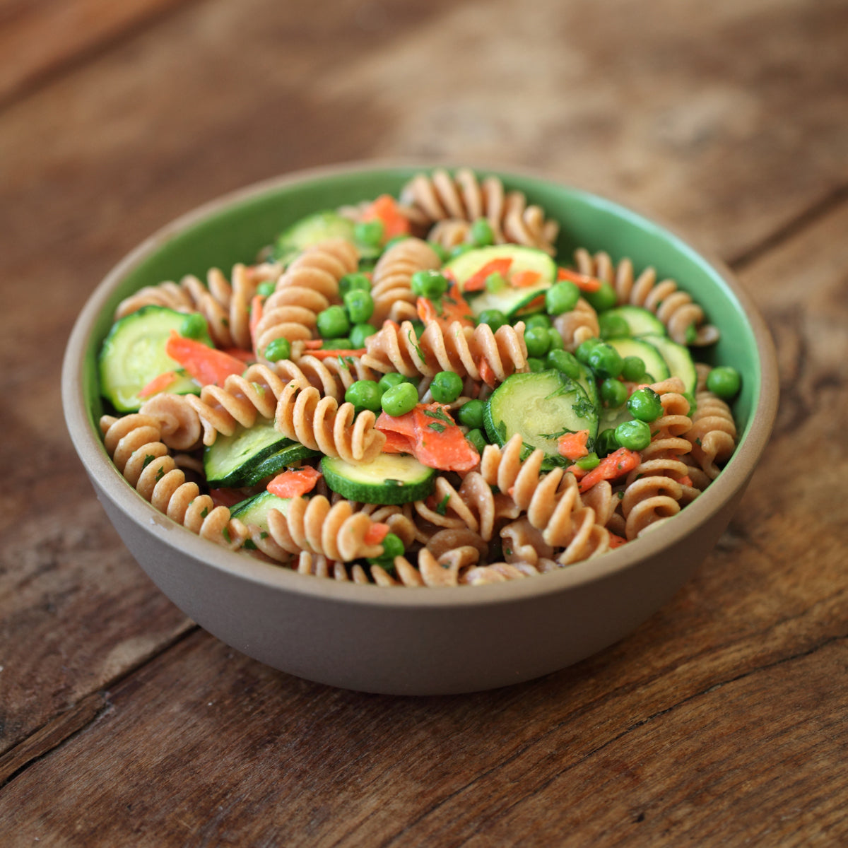 Close-up of Organic Einkorn Whole Wheat Fusilli showing whole-grain spiral shape and coarse texture in a ceramic bowl on a wooden table