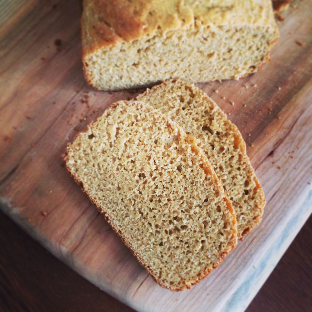 Sliced golden einkorn whole wheat loaf on a wooden cutting board