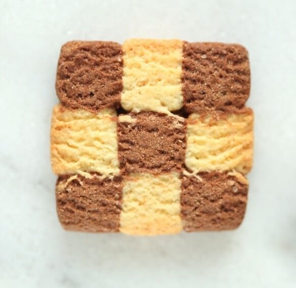 Top-down view of an Organic Einkorn checkerboard cookie showcasing alternating chocolate and vanilla shortbread squares with a pale marble background