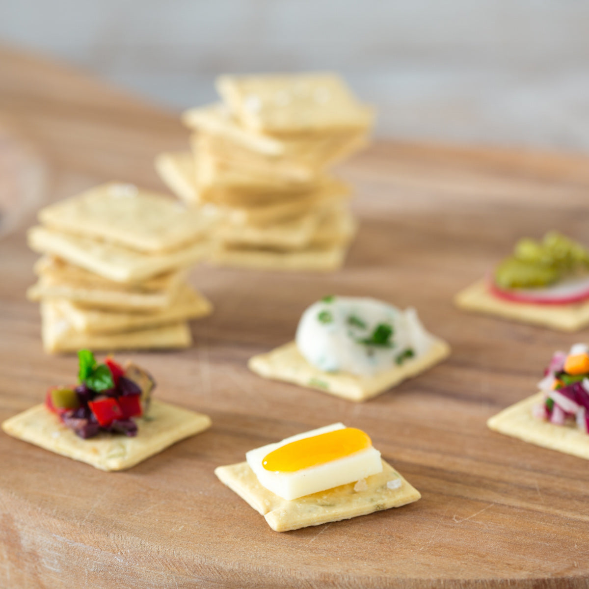 Close-up of Organic Einkorn Sourdough Rosemary Crackers showing rosemary flecks and crisp texture on a wooden serving board