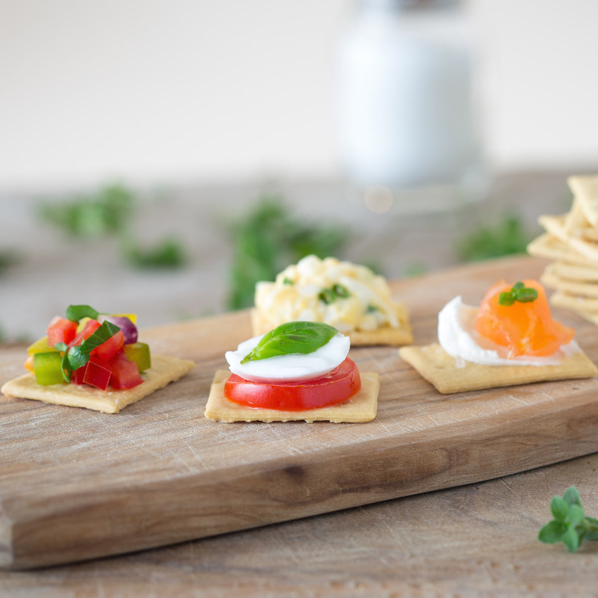 Close-up of Organic Einkorn Sourdough Sea Salt crackers topped with tomato and mozzarella on a wooden board