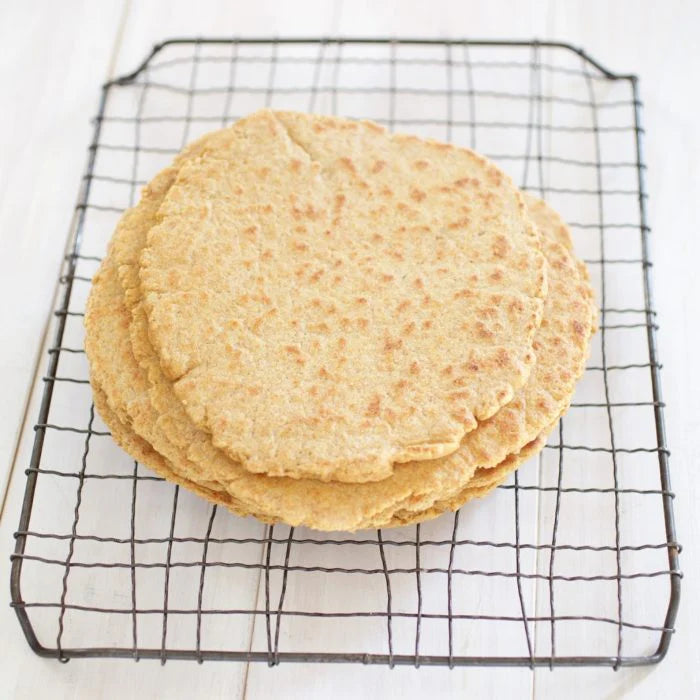 Overhead view of stacked whole-grain einkorn flatbreads showcasing golden-brown tops on a wire cooling rack