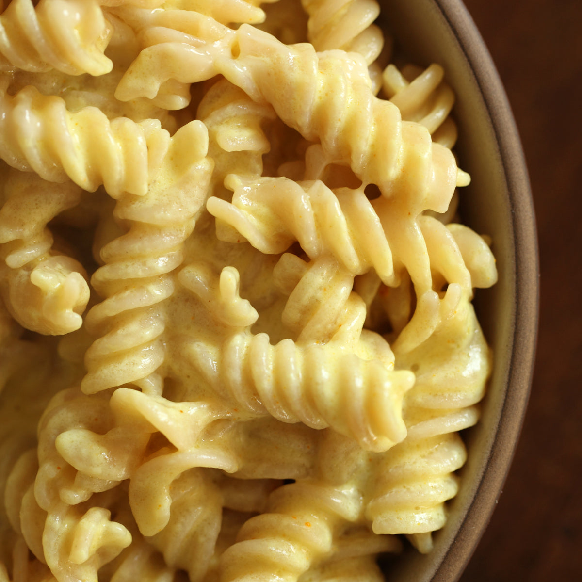 Gluten-free organic brown rice fusilli tossed in creamy mac and cheese and served in a shallow bowl