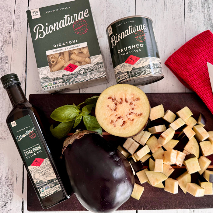 Bionaturae rigatoni, crushed tomatoes, extra virgin olive oil, whole and diced eggplant and basil on a cutting board