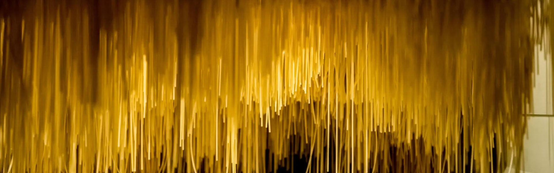 Golden pasta (spaghetti) strands hanging to dry in a traditional pasta-making facility.