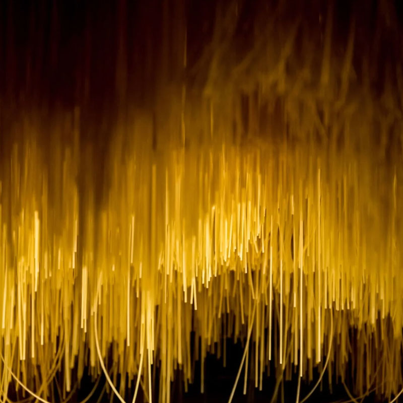Close-up abstract of uncooked golden spaghetti strands hanging like a curtain with warm backlighting.