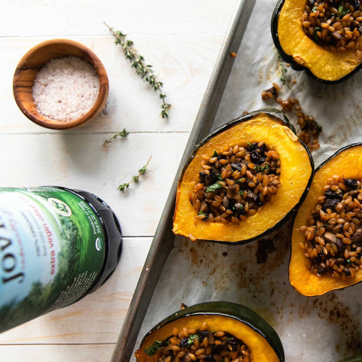 Roasted acorn squash halves stuffed with organic Einkorn wheat berries and herbs on a baking sheet