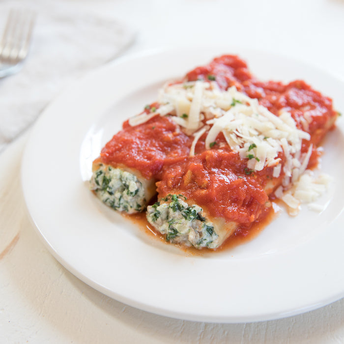 Close-up of gluten-free turkey and spinach manicotti with ricotta filling, tomato sauce, and shredded cheese