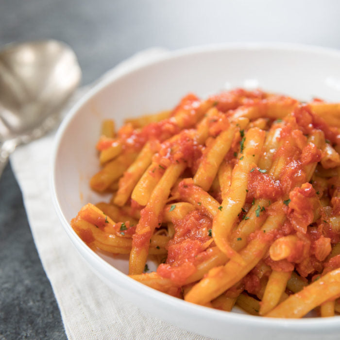 Yellow wax beans braised in tomato sauce served in a white bowl on a cloth napkin