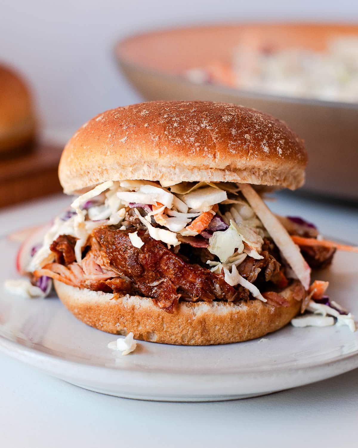 Pulled pork sandwich piled with slaw on a bun made from Traeger-smoked pork shoulder.