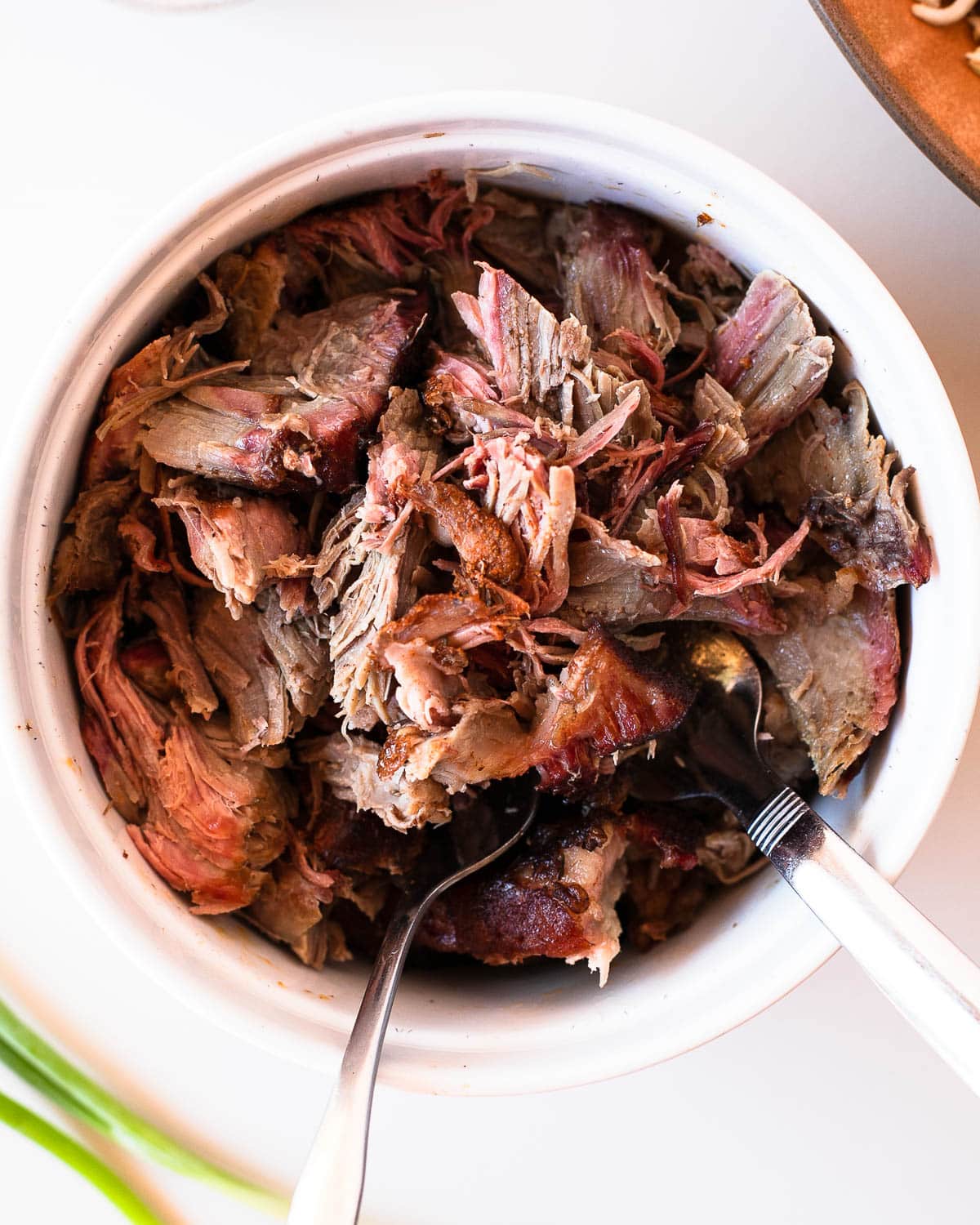 Close-up of tender shredded pulled pork with bits of smoky bark.