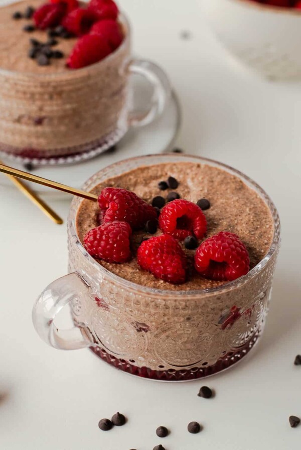 blended overnight oatmeal in a mug with raspberries on top