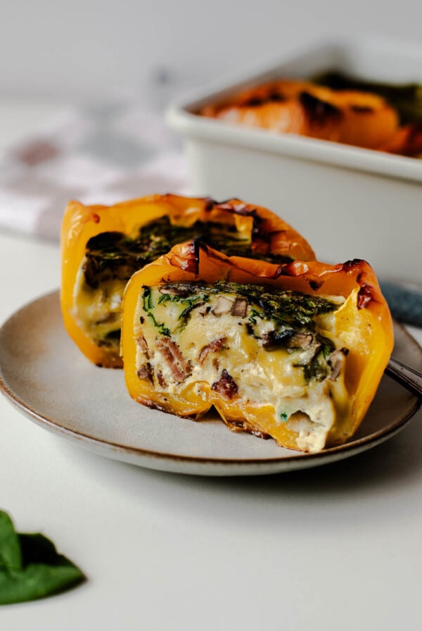 Close-up of breakfast stuffed pepper half, creamy eggs with bacon and spinach.