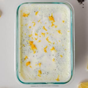 Lemon chia pudding mixture sprinkled with fresh lemon zest before chilling.