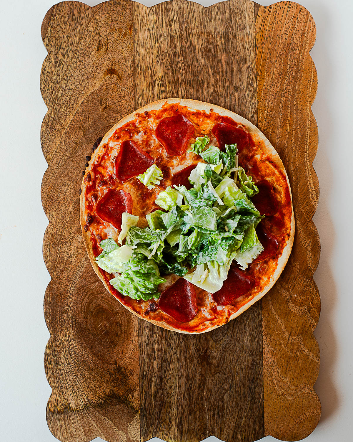 Pepperoni tortilla pizza topped with Caesar salad romaine and dressing