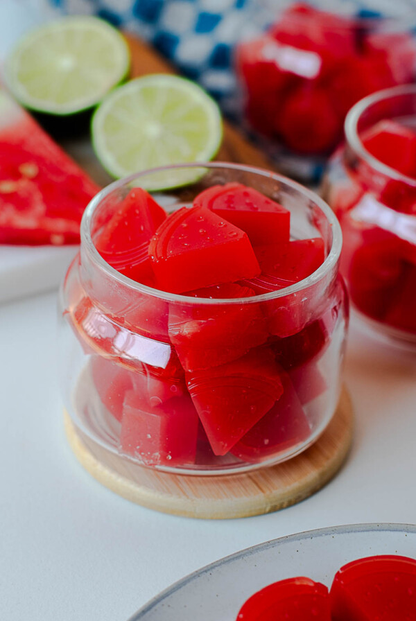 Glass jars filled with set watermelon gummies shaped like small wedges.
