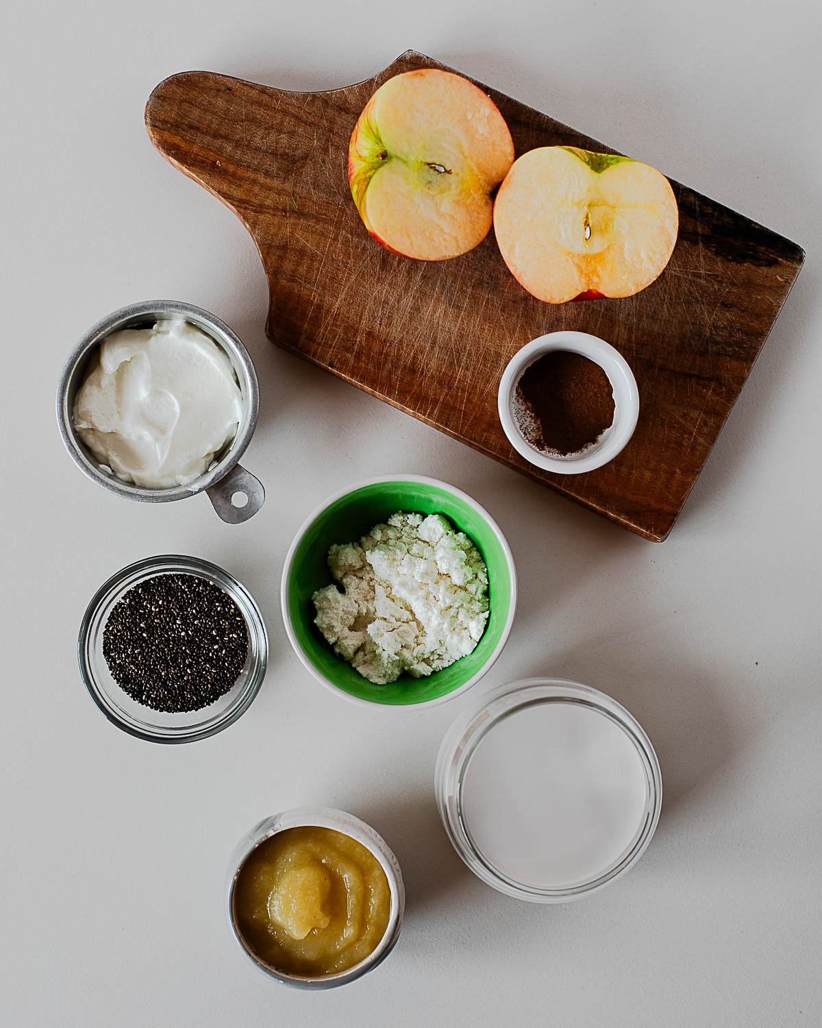Ingredients for apple pie chia pudding including Greek yogurt, applesauce, chia seeds, and cinnamon