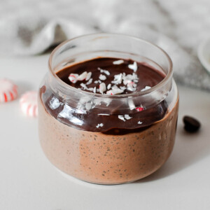 Chocolate peppermint chia pudding in a glass jar with a dark chocolate shell and crushed candy canes