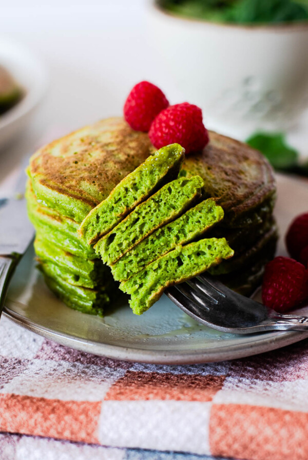 Fork cutting into soft green einkorn pancakes showing fluffy interior